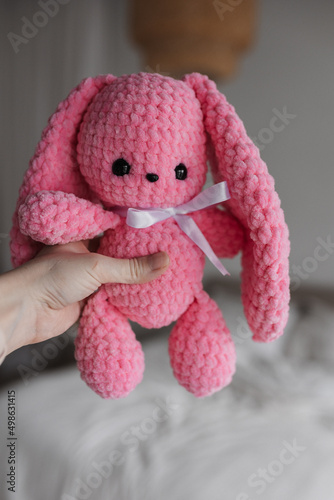 Knitted pink-colored bunny in the interior of a bright apartment