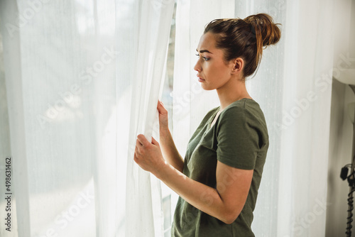 Woman Feeling Worried While Standing Near The Window At Home Free Download Woman Feeling Worried While Standing Near The Window At Home - GFXLoad