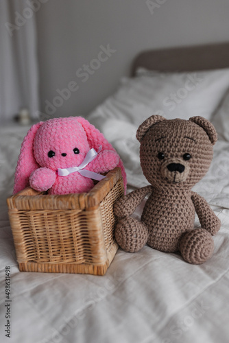 Knitted toy bunny pink and brown bear in a bright room