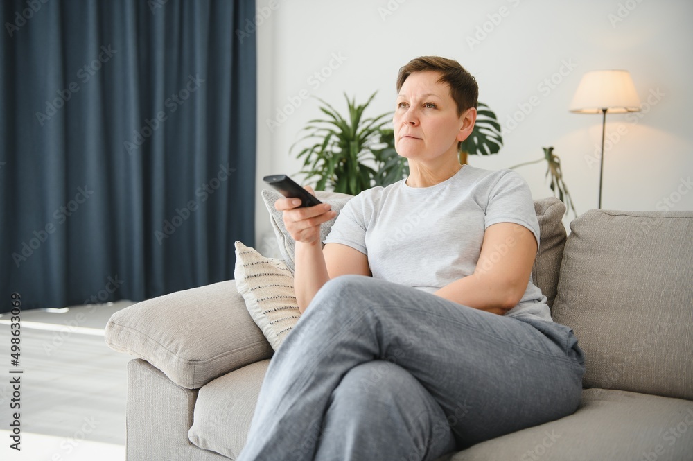 Portrait of happy older woman changing channel on television. Portrait of happy older woman changing channel on television.
