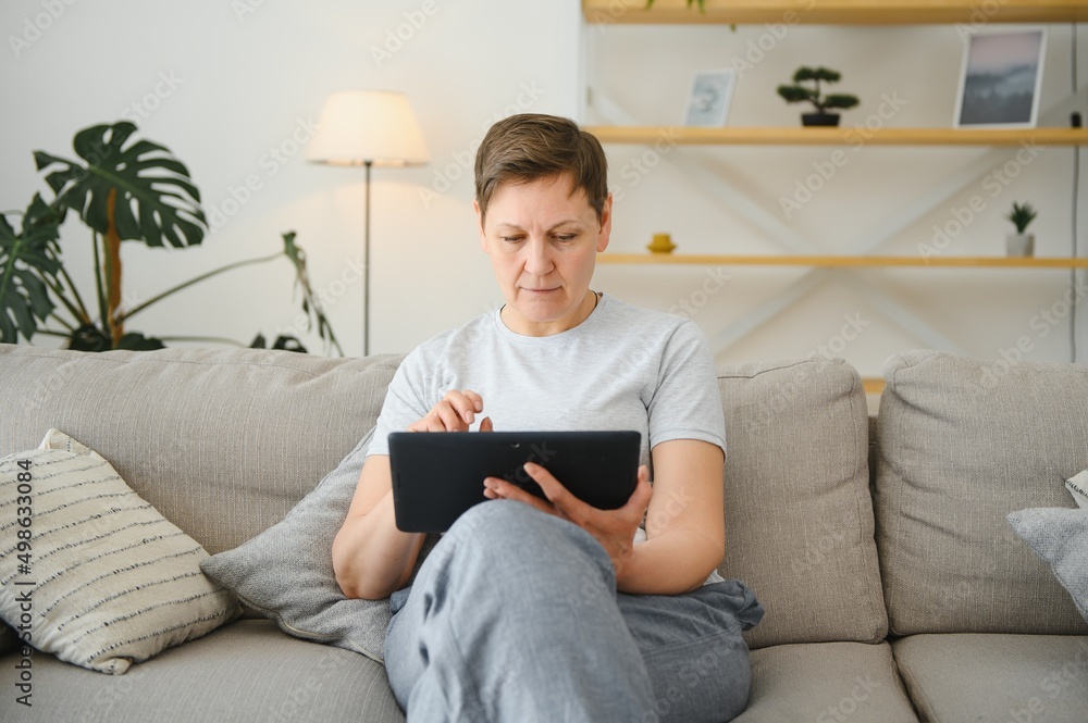 people, technology and internet concept - happy middle aged woman with tablet pc computer at home. people, technology and internet concept - happy middle aged woman with tablet pc computer at home.