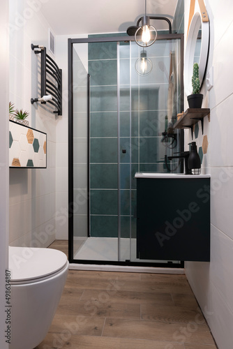 Interior of bathroom in modern style. Cabin of shower  toilet  wooden floor and cabinet with bathroom sink. Vertical.