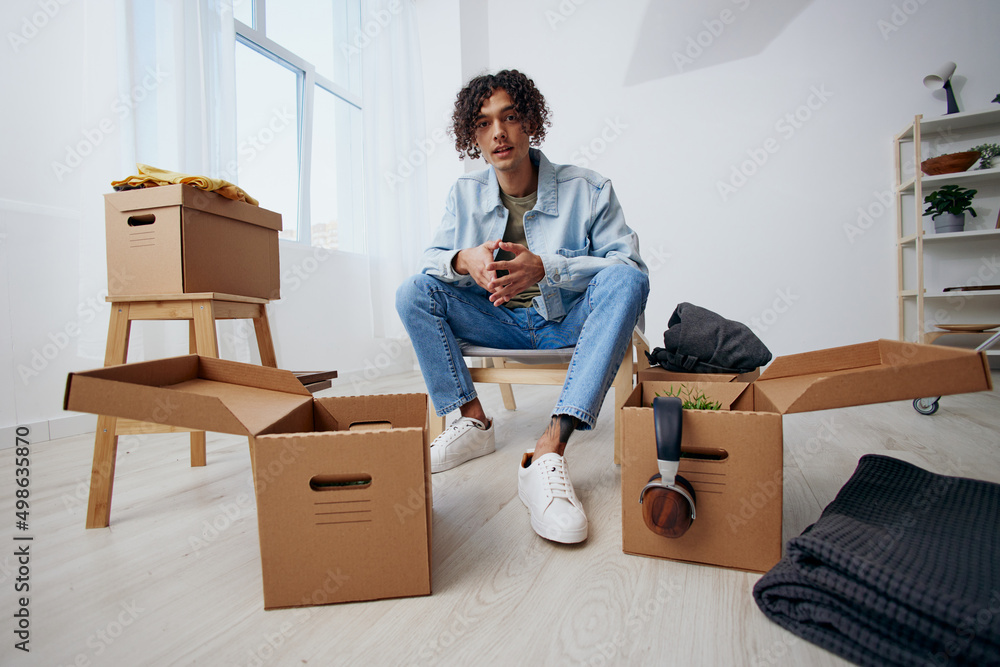 handsome guy sitting on a chair with boxes moving interior handsome guy sitting on a chair with boxes moving interior