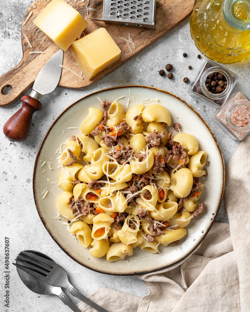 Pasta Pipe Rigate with stew In Bianco in a plate on a gray culinary background. Traditional Italian pasta with ground beef on the kitchen table closeup