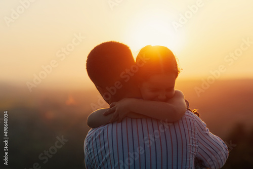 Obraz na płótnie The little cute daughter hugs his father in nature at sunset. Amazing sunset, close up. w salonie