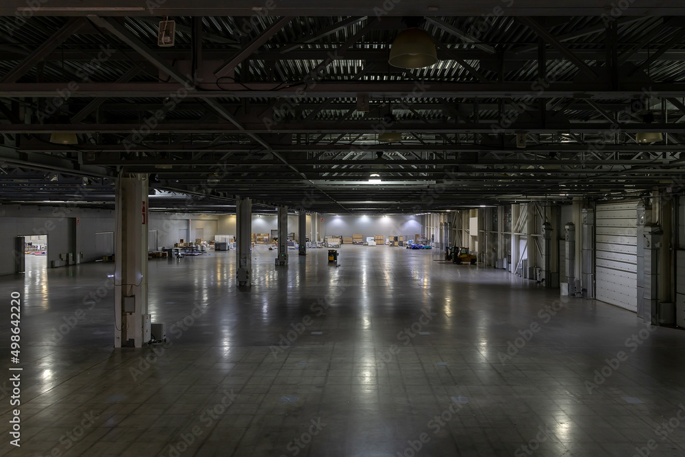 Huge empty metal hangar. A room for creating a warehouse or storing large-sized objects. Modern large garage with emergency lighting