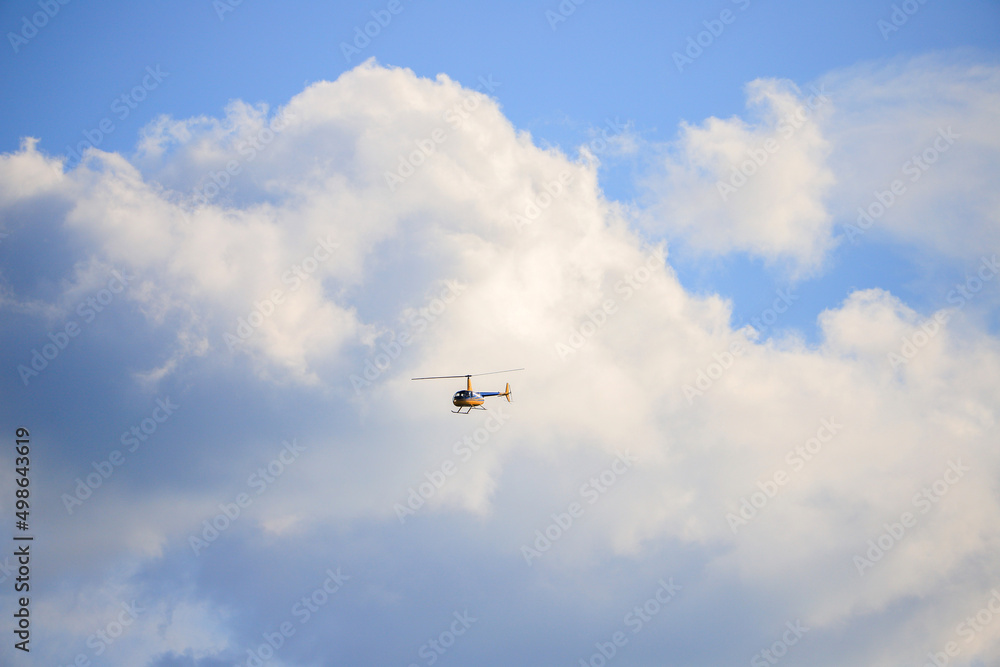 Helicopter Robinson R44 flies in the clouds