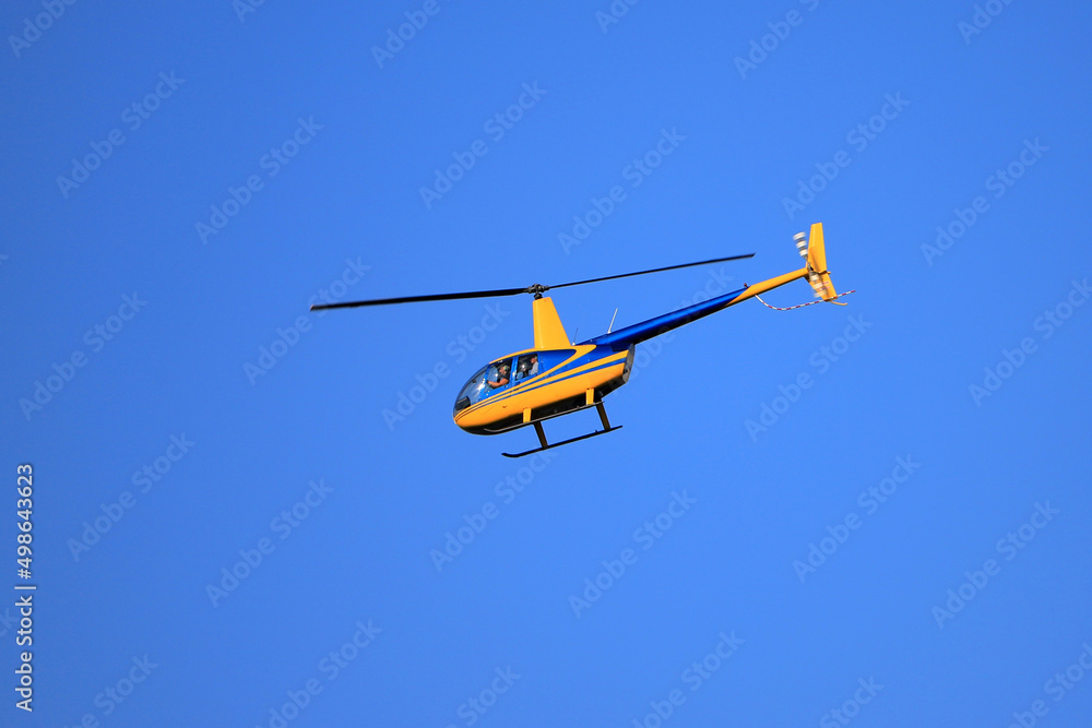 Helicopter Robinson R44 flies in the blue sky