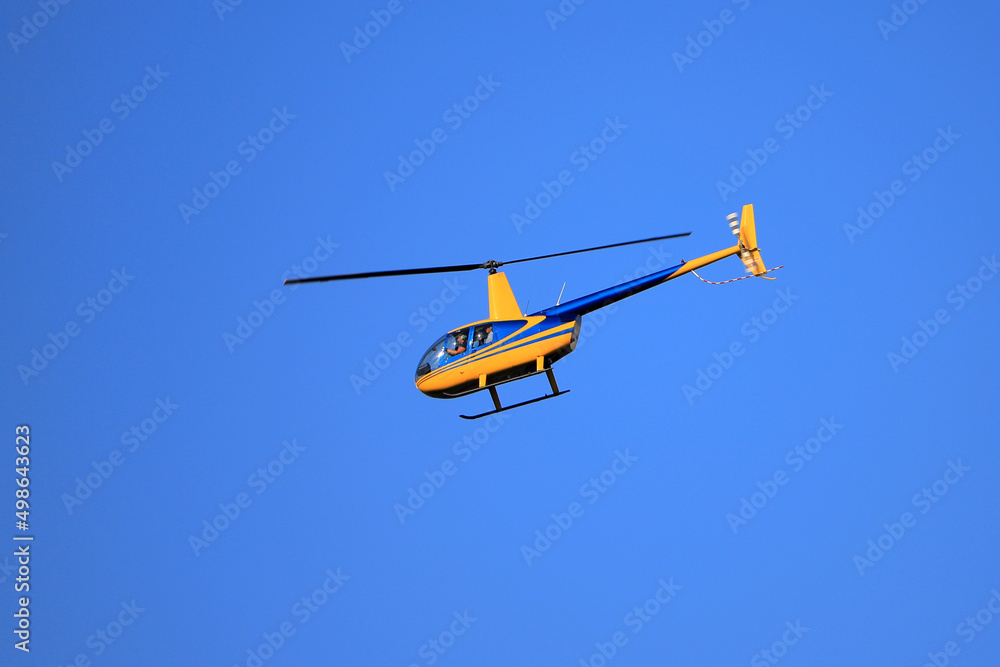 Helicopter Robinson R44 flies in the blue sky Helicopter Robinson R44 flies in the blue sky