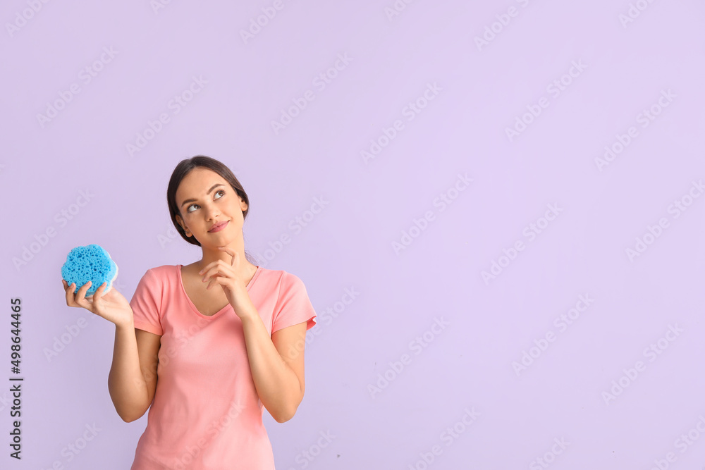 Thoughtful young woman with sponge on color background Thoughtful young woman with sponge on color background