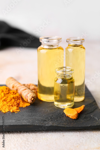 Bottles of oil, turmeric root and powder on light background