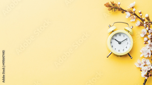 Spring background may flowers and April floral nature with alarm clock on yellow. Branches of blossoming apricot macro with soft focus. For easter and spring greeting cards, copy space. Springtime.