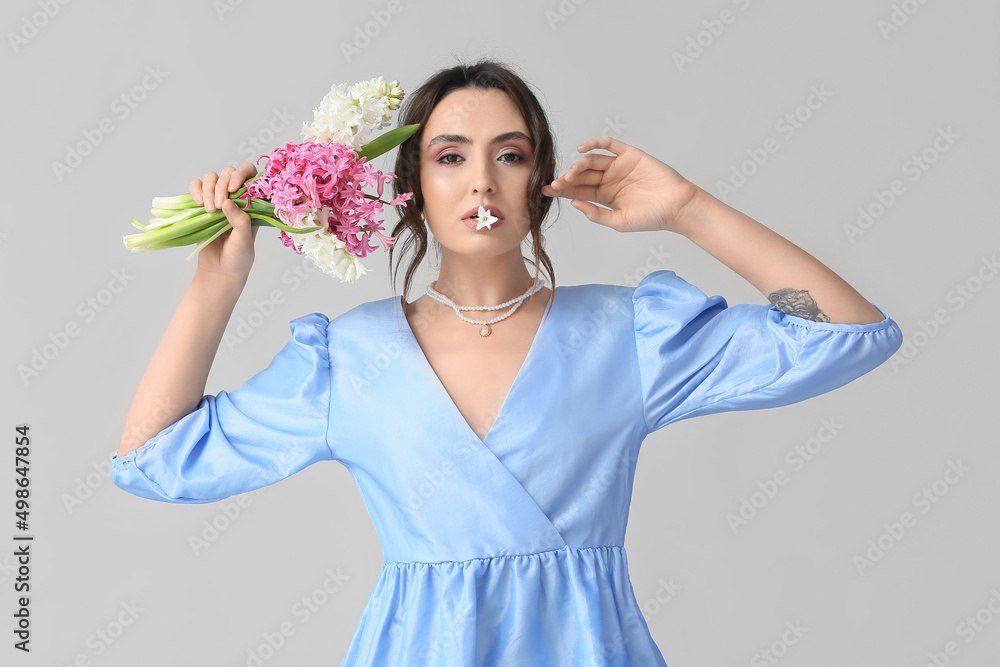 Pretty young woman with hyacinth flowers on grey background Pretty young woman with hyacinth flowers on grey background