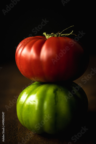 close up of red and green tomatoes in a stack on a dark background