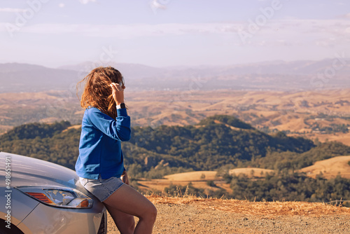 Young woman leaned to her car, stopped with a view during road trip © Diana Vyshniakova