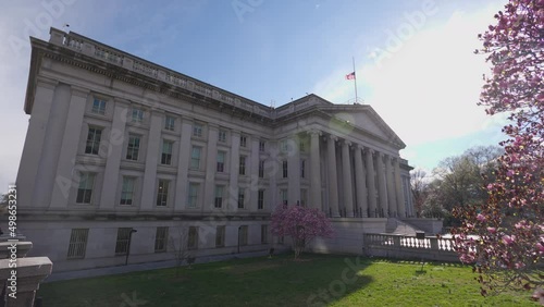 The north entrance of the U.S. Department of the Treasury Building in downtown Washington, D.C. seen on a sunny spring day. A tree with blossoming pink flowers is seen in the foreground. photo