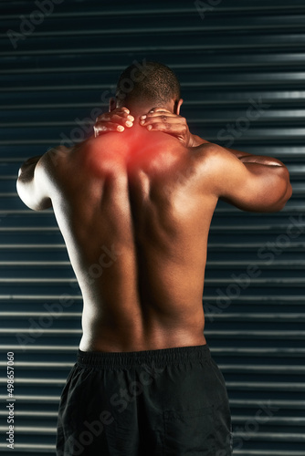 Carrying a little tension in his neck. Rearview shot of an athletic young man holding his neck in pain during a workout.