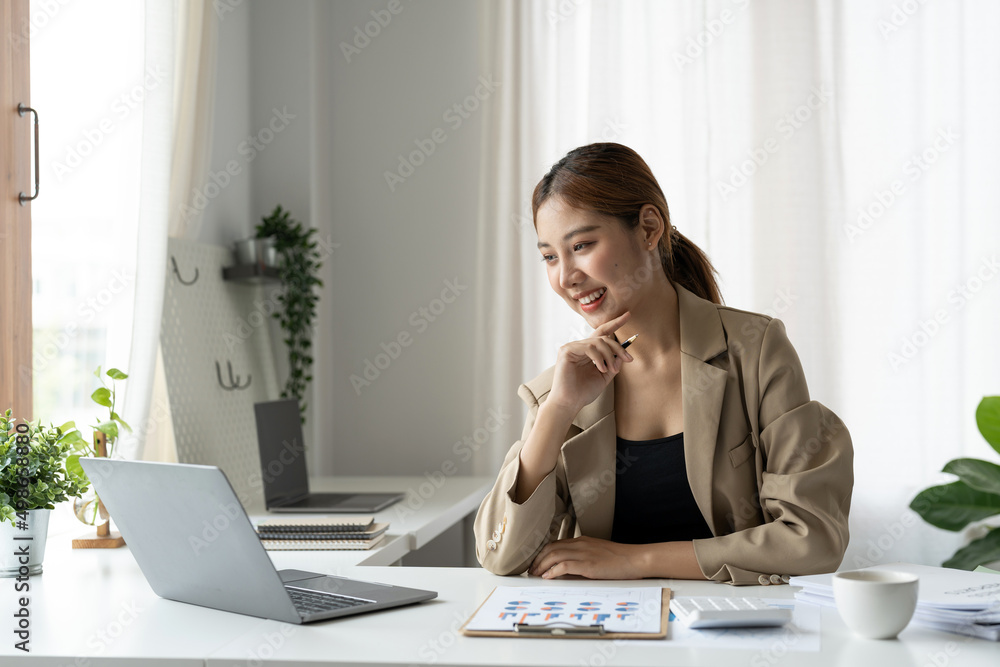 Business asian woman using laptop computer for do math finance on wooden desk in office, tax, accounting, financial concept Business asian woman using laptop computer for do math finance on wooden desk in office, tax, accounting, financial concept