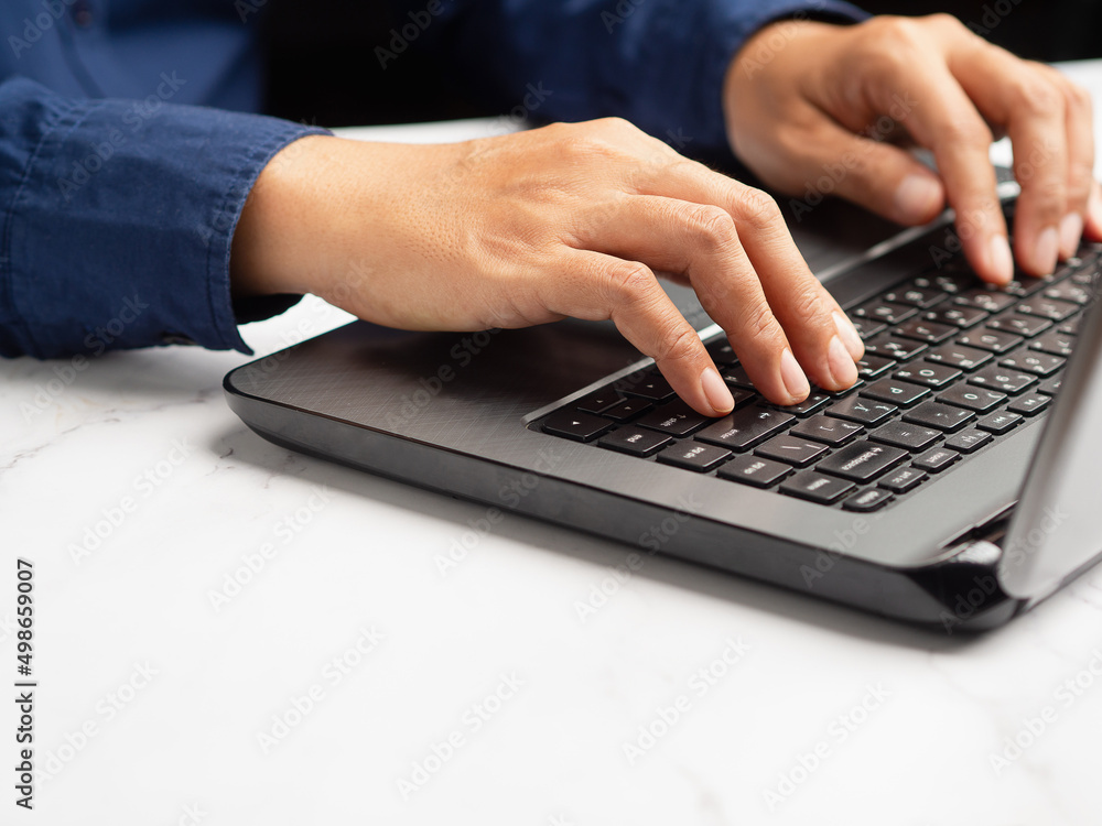 Close-up of hands businessman using a laptop on a marble table