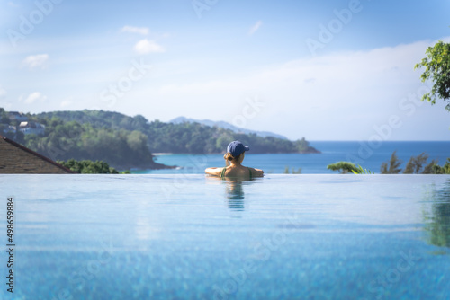 woman relaxing in the swimming pool looking the sea, Ocean in travel vacation, Phuket Thailand.