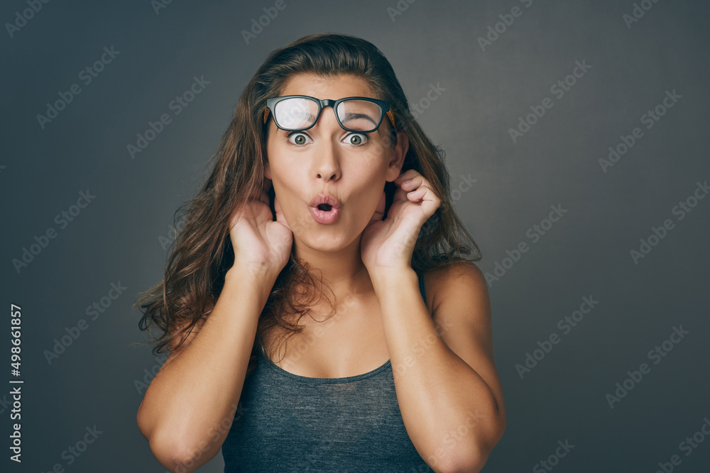Expect the unexpected. Studio shot of an attractive young woman looking surprised against a grey background.