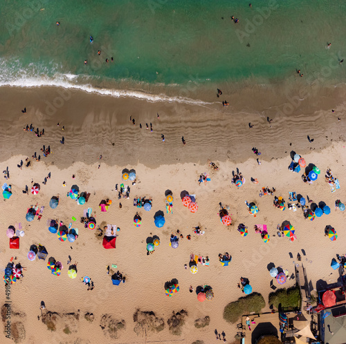 Colorido paisaje en playa. Verano para disfrutar arena, sol, mar y calor. Sombrillas playeras desde drone. © Cristian