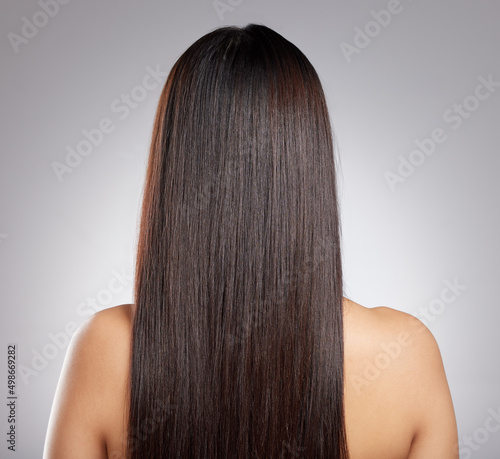 Simply sleek strands. Rearview shot of a young woman with long silky hair posing against a grey background.