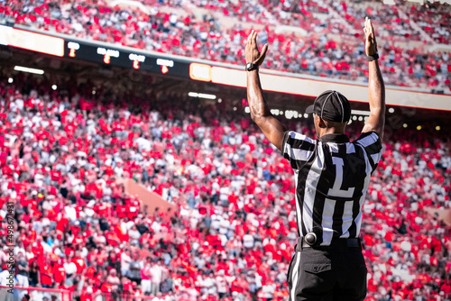 American Football Referee official signals a touchdown in a large football stadium. 