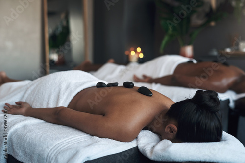 Theres no better feeling than a deep massage. Shot of a young woman getting a hot stone massage at a spa. photo