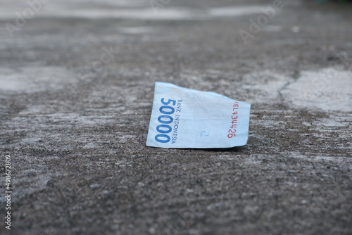 selective focus on Indonesian 50,000 rupiah banknotes falling on the concrete floor