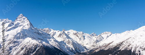 Panoramic view of winter snowy mountains in Caucasus region in Russia with blue sky © SDF_QWE