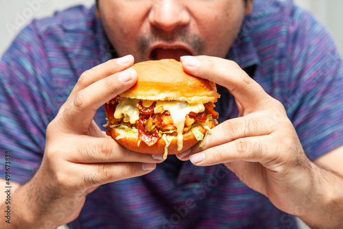 Eastern man looking at crispy chicken burger and is about to eat it.