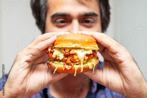 Eastern man looking at crispy chicken burger and is about to eat it.