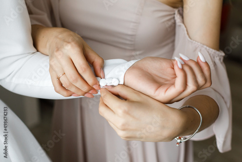 Woman helps bride to fix her sleeve covered