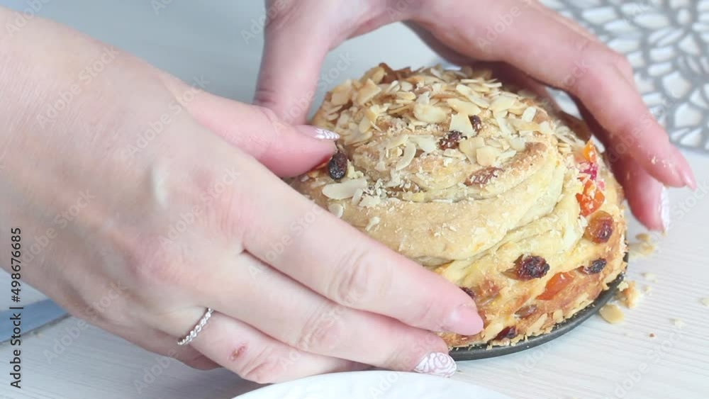 A woman cuts a cooked cruffin with raisins and candied fruits with a knife. Close-up. A woman cuts a cooked cruffin with raisins and candied fruits with a knife. Close-up.