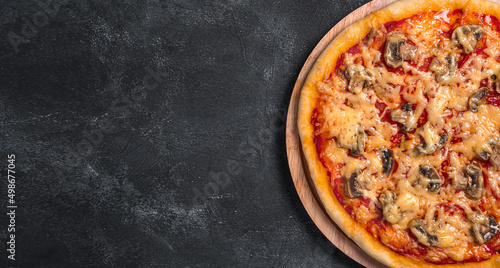 Homemade, delicious pizza with tomatoes, mushrooms and cheese on a dark background.