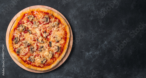 Juicy pizza with tomatoes, mushrooms, cheese and tomato sauce on a board on a dark background.