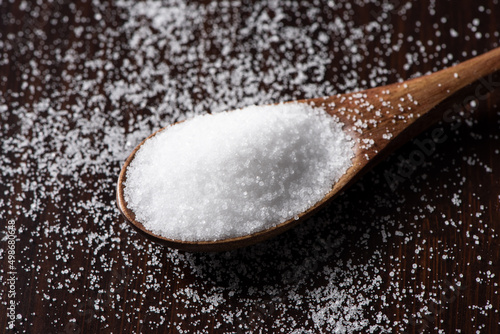 salt in a wooden spoon on table.