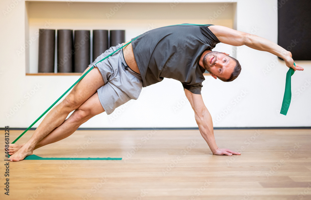 Naklejka premium Fit muscular man doing a resistance band exercise