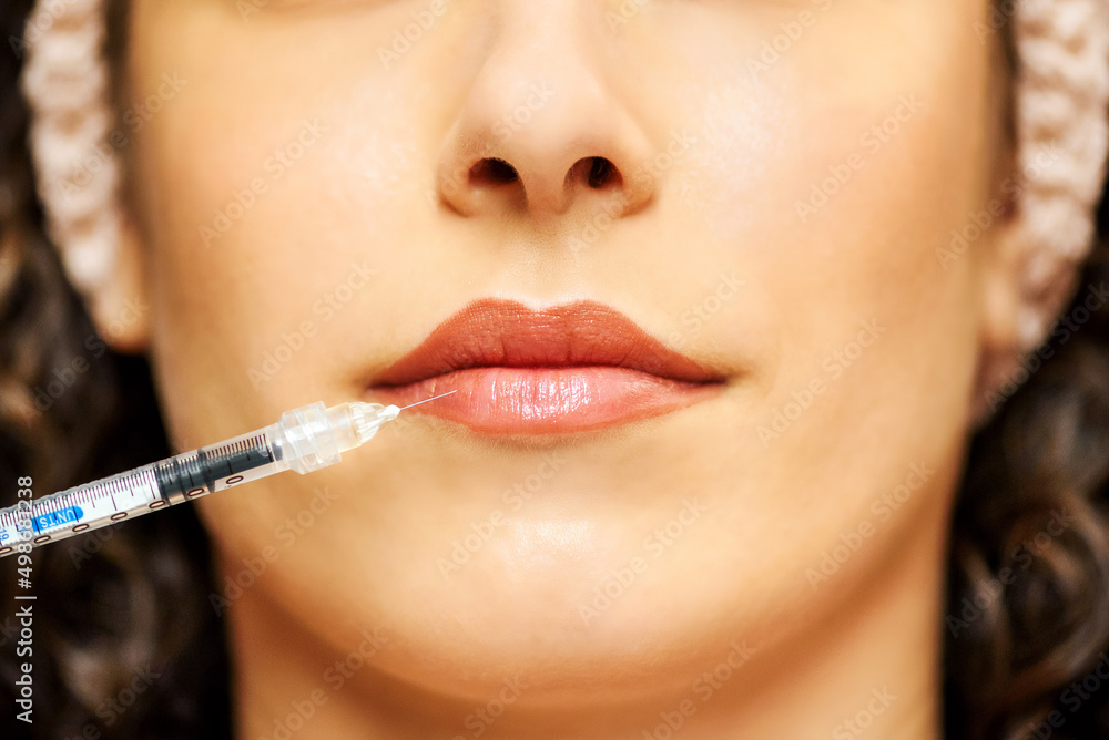 Crop woman with medical syringe against lips Crop woman with medical syringe against lips