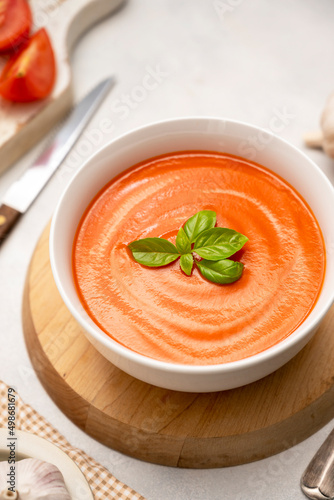 Tomato soup with fresh basil in white bowls. Bright background. Vegan creamy soup.