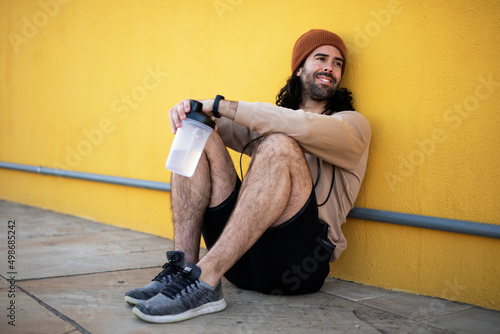 Young thirsty athletic man outside. Fit handsome man resting after training
