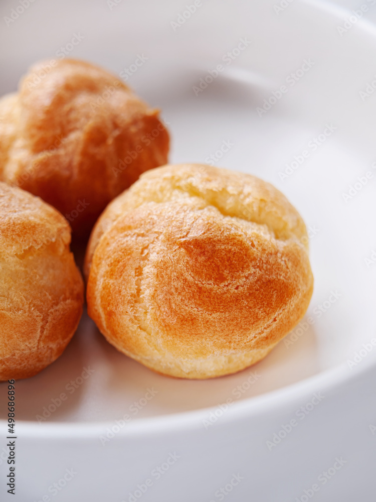 Fresh profiteroles close-up in a white plate. Vertical. Selective focus Fresh profiteroles close-up in a white plate. Vertical. Selective focus
