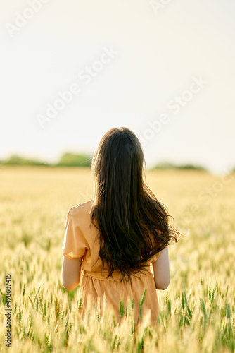 girl in a wheat field with her back with flying hair
