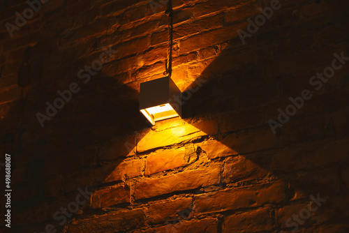 Warm light close up photo of a wall lamp on bricks with copy space for your text.