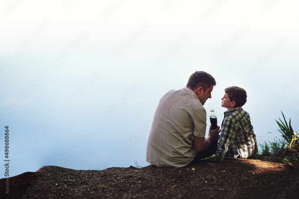 Spending some quality father-son time. Shot of a father and his young son sharing a soda while relaxing outside.