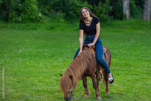 girl riding a pony on a green lawn © zokov_111