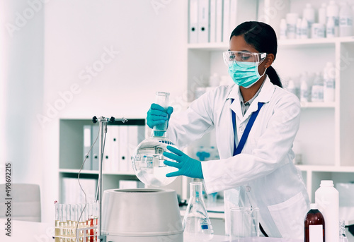 Shes got an experiment to do. Cropped shot of an attractive young female scientist placing a florence flask with a liquid into a centrifuge while working in a laboratory.