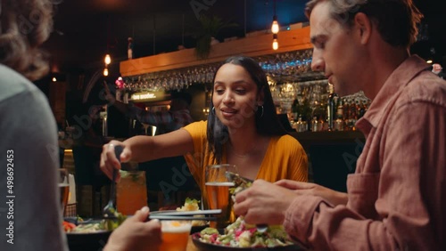 Diverse group of friends eating out at restaurant tasting food photo