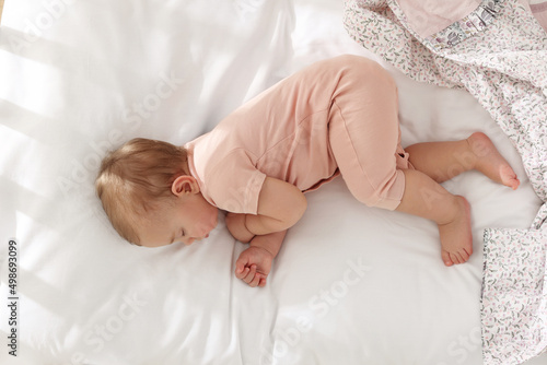 Cute little baby sleeping on soft bed, top view photo